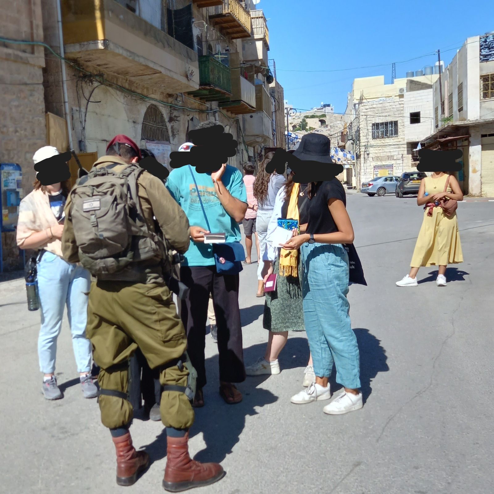 A soldier checks IDs on a street in H2 Hebron.